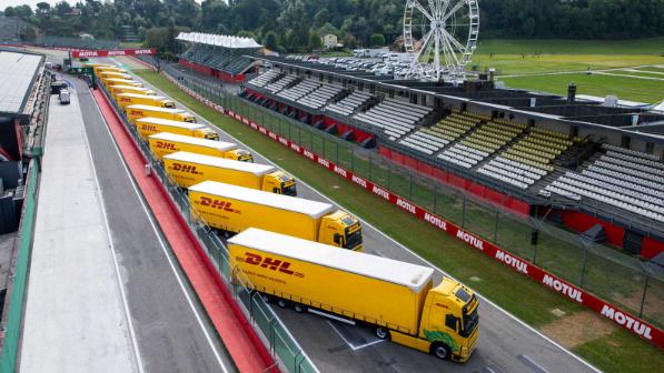 DHL trucks parked on the start/finish straight of a racetrack.