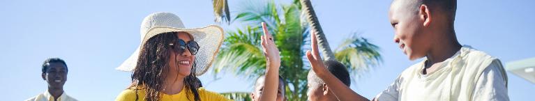 Eine Frau mit einem großen Hut gibt einem Jungen einen High-five. 