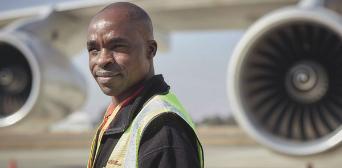 A man with a safety vest in front of a plane