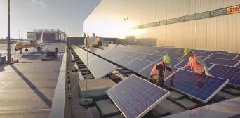 Two workers adjusting a solar panel. 