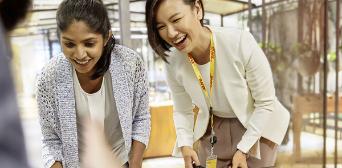 Two office workers looking at something on a table.