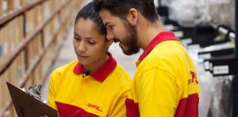 Two DHL employees in DHL T-Shirts looking at a clipboard.