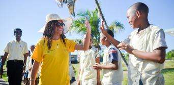 A woman in a yellow DHL t-shirt giving a high-five to a young child.