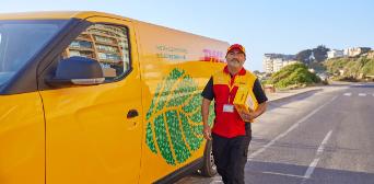 A DHL-van in front of three houses