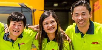 Three colleagues in neon-yellow shirts with their arms wrapped around each other's shoulders. 