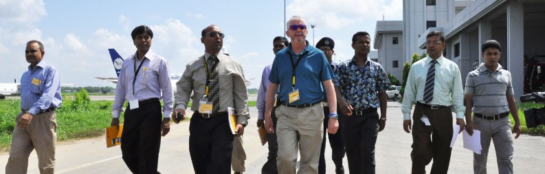 A group of men with yellow lanyards at an airport terminal.