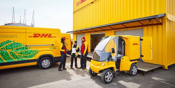 Three DHL employees standing between DHL vehicles.