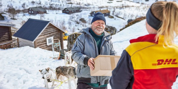 A courier delivering a parcel to an old man with sledge dogs. 