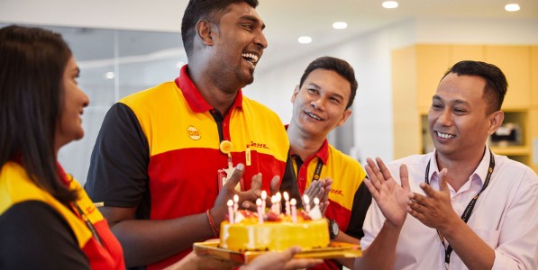 Four DHL employees celebrating a birthday with cake. 