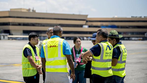 A group of people, party in safety vests, discussing and gesticulating.