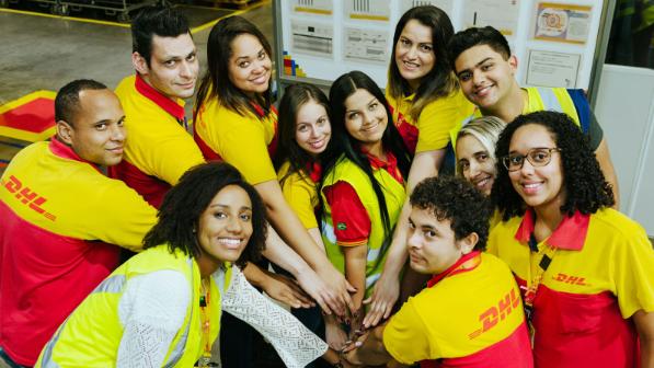 A group pf DHL employees put their hands together while standing in a circle.