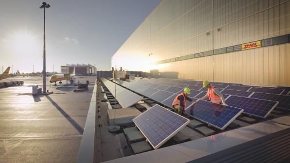 Two men in safety vests checking solar panels. 