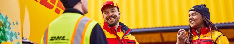 Three DHL employees smiling at each other. 