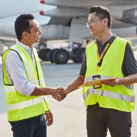 Two men in yellow safety vests shaking each other's hand.