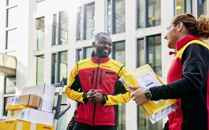 Two couriers with different skin colors talking to each other.