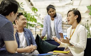 Three young employees listen to a more mature colleague.