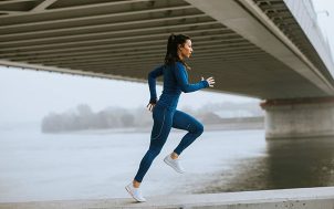 A woman in running gear jogging along a river.