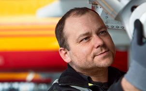 A man checking a part of a DHL plane.